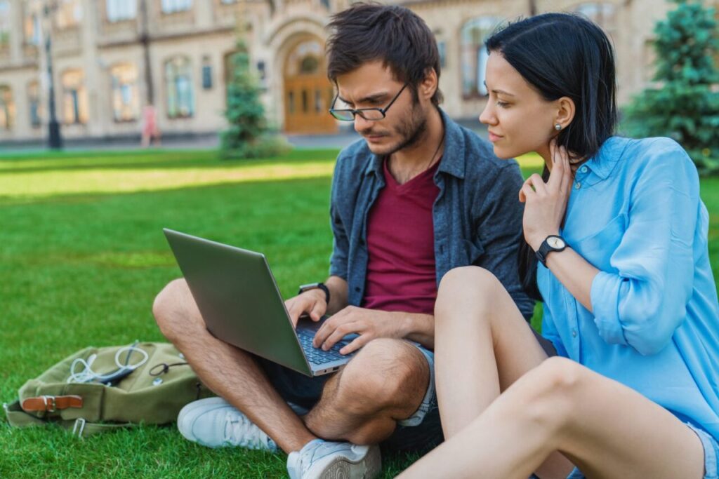 Étudiant consultant une plateforme en ligne sur son ordinateur portable dans un espace de travail universitaire.